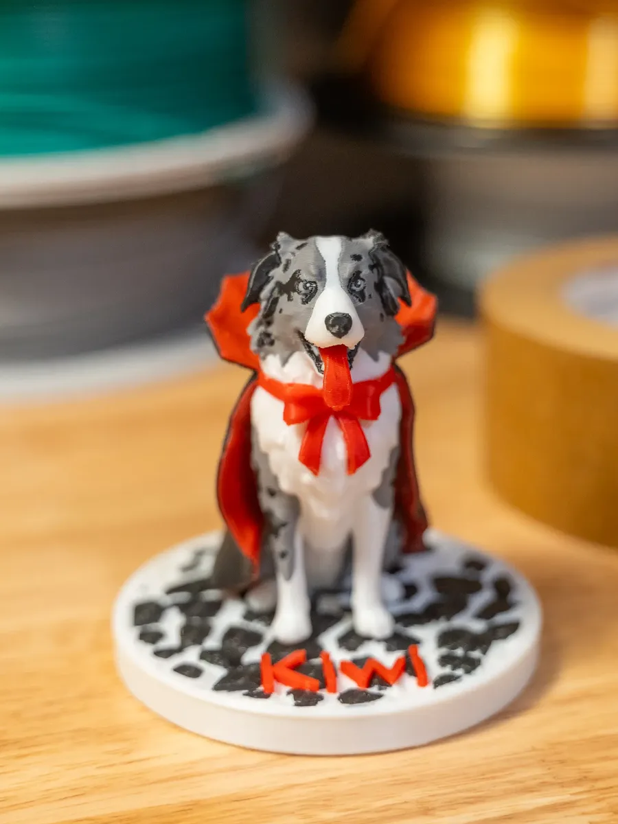 The finished 3D-printed MiniMe figurine of the dog in its red costume on a round base